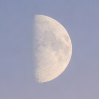 Partial view of the moon visible against a deep dark blue night sky
